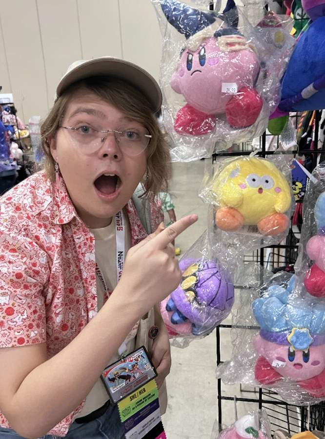 Reese surrounded by Kirby merch at a convention booth